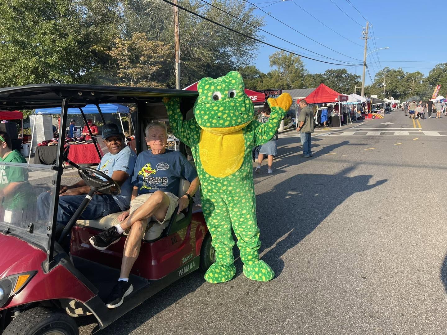 Ribbet waving beside a golf cart shuttle on Main Street