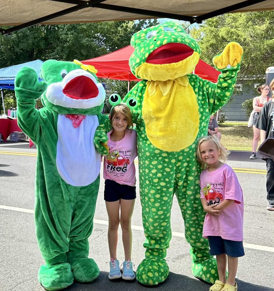 Ribbet and Lilly posing with two girls in Frog Festival shirts