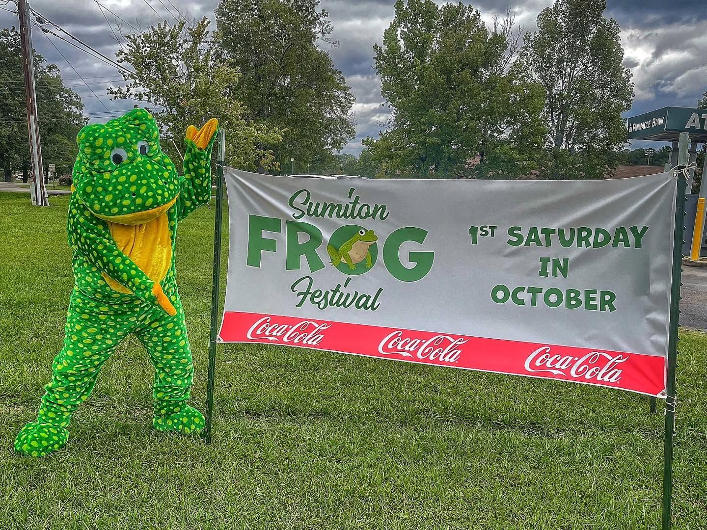 Ribbet next to the Sumiton Frog Festival banner: 1st Saturday in October